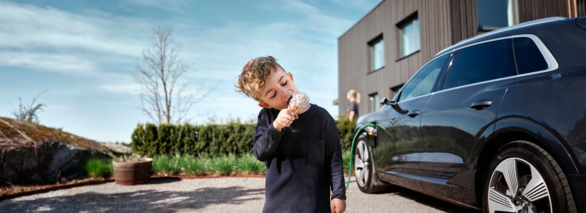 Illustrasjonsbilde av en gutt som spiser is mens en elbil lader i bakgrunnen.