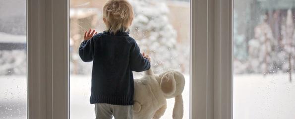 Et barn som ser på snø ut av vinduet